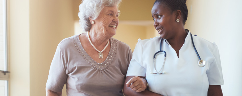 Personal care aide helping a client walk at home